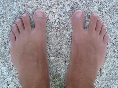 Gerald's freshlytanned feet contrast with the white sand in the petanque 